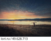 Person walking a country road carrying dry firewood. Peaceful sunset scene and wanderer silhouette on trail. Idyllic rural landscape. Стоковое фото, агентство Ingram Publishing / Фотобанк Лори