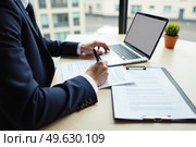 Бизнесмен за работой с документами и ноутбуком / A businessman at work with documents and a laptop. Стоковое AI-изображение, AI-художник Валерий Лукин / Фотобанк Лори