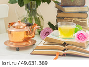 Summer teatime - cup of tea in glass with old books, rose flower and teapot. Cup of tea with books. Стоковое фото, агентство Ingram Publishing / Фотобанк Лори