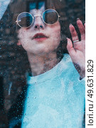 Sad woman alone in her home looking through a window in a rainy day. Стоковое фото, агентство Ingram Publishing / Фотобанк Лори