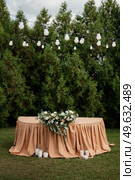 The presidium of the newlyweds in the banquet hall of the restaurant is decorated with candles and green plants, wisteria hangs from the ceiling. Стоковое фото, агентство Ingram Publishing / Фотобанк Лори