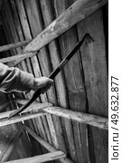Person gripping a metal prying tool inside a weathered wooden structure. Стоковое фото, фотограф EugeneSergeev / Фотобанк Лори