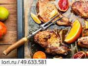 Pork cutlet on the bone roasted in oranges, lime and tangerine.. Meat steak fried with citrus fruits. Стоковое фото, агентство Ingram Publishing / Фотобанк Лори