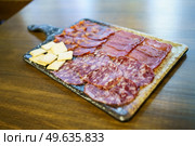 Iberian cured meats platter. A typical dish of Spanish cuisine. with crackers placed on board on lumber restaurant table. Iberian cured meats platter. A typical dish of Spanish cuisine. Стоковое фото, агентство Ingram Publishing / Фотобанк Лори