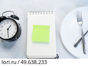 Intermitted farsting diet concept - empty plate with fork and knife and timer. Intermitted farsting diet concept. Стоковое фото, агентство Ingram Publishing / Фотобанк Лори