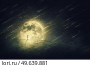 Starfall painting of a surreal world and a person silhouette on a desolate land. Starry night with falling comets and full moon. Стоковое фото, агентство Ingram Publishing / Фотобанк Лори