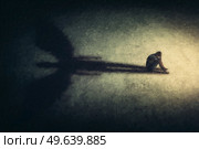 Surreal painting of a man sitting alone isolated in a dark room, casting a shadow of a powerful guardian angel. Inner strength metaphor. Introvert person found an imaginary friend. Стоковое фото, агентство Ingram Publishing / Фотобанк Лори