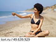 Positive black woman in bikini sitting playing with sand on the beach. African American girl tanning.. Positive black woman in bikini sitting playing with sand on the beach. Стоковое фото, агентство Ingram Publishing / Фотобанк Лори
