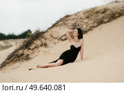 girl in a black long dress in a sandy desert under a blue sky. Стоковое фото, агентство Ingram Publishing / Фотобанк Лори