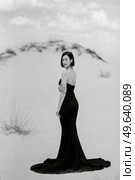 girl in a black long dress in a sandy desert under a blue sky. Стоковое фото, агентство Ingram Publishing / Фотобанк Лори
