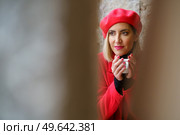 View through blurred column of charming female in red beret looking away while sitting with cup of coffee in hands. Attractive woman with coffee in cafe. Стоковое фото, агентство Ingram Publishing / Фотобанк Лори
