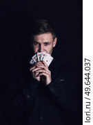 Successful poker player holds up a winning royal flush combination. Lucky gambler with playing cards on a dark background. Casino tournament winner, victory concept. Стоковое фото, агентство Ingram Publishing / Фотобанк Лори