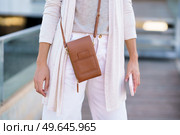 Unrecognisable woman standing near an office building carrying a handbag and a smartphone. Caucasian female in urban background.. Unrecognisable woman standing near an office building carrying a handbag and a smartphone. Стоковое фото, агентство Ingram Publishing / Фотобанк Лори