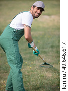handsome young man raking leaves in garden. Стоковое фото, агентство Ingram Publishing / Фотобанк Лори