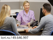 doctor talking to pregnant couple at a hospital. Стоковое фото, агентство Ingram Publishing / Фотобанк Лори