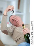 drunken man holding bottle of drink looking at car keys. Стоковое фото, агентство Ingram Publishing / Фотобанк Лори