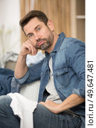 unmotivated man sighing as he does the laundry. Стоковое фото, агентство Ingram Publishing / Фотобанк Лори