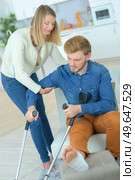 Lady helping man with crutches to stand up. Стоковое фото, агентство Ingram Publishing / Фотобанк Лори