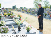man stood looking respectfully at gravestone. Стоковое фото, агентство Ingram Publishing / Фотобанк Лори