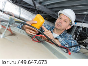 electrician inspecting the dead wires on the ceiling top. Стоковое фото, агентство Ingram Publishing / Фотобанк Лори