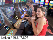 gilrs playing slot machines in a casino. Редакционное фото, агентство Ingram Publishing / Фотобанк Лори