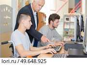 Tutor helping handicapped student on computer. Стоковое фото, агентство Ingram Publishing / Фотобанк Лори