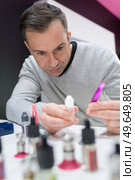 mature seller manipulating modes in vape store. Стоковое фото, агентство Ingram Publishing / Фотобанк Лори