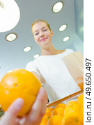 Closeup of orange, lady holding paper bag in background. Стоковое фото, агентство Ingram Publishing / Фотобанк Лори