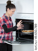 young woman removing cooked tart from the oven. Стоковое фото, агентство Ingram Publishing / Фотобанк Лори