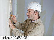 mature male builder stripping wallpaper with scraper. Стоковое фото, агентство Ingram Publishing / Фотобанк Лори