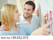Couple holding color sampler against wall. Стоковое фото, агентство Ingram Publishing / Фотобанк Лори