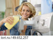 woman pouring fabric softener into washing machine drawer. Стоковое фото, агентство Ingram Publishing / Фотобанк Лори