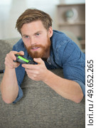 young man playing videogames on couch. Стоковое фото, агентство Ingram Publishing / Фотобанк Лори