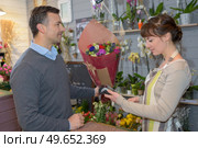 smiling woman seller offering flowers male client. Стоковое фото, агентство Ingram Publishing / Фотобанк Лори
