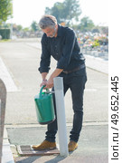 Man filling watering can in cemetary. Стоковое фото, агентство Ingram Publishing / Фотобанк Лори