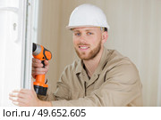 tradesman using cordless screwdriver to work on pvc door. Стоковое фото, агентство Ingram Publishing / Фотобанк Лори