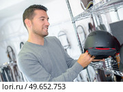 Man looking at horse riding helmet. Стоковое фото, агентство Ingram Publishing / Фотобанк Лори