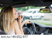 woman applys lipstick in front of rearview mirror in car. Стоковое фото, агентство Ingram Publishing / Фотобанк Лори