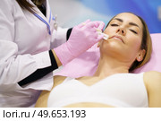 Doctor painting the area of a middle-aged woman’s face where the PDO suture treatment threads will be injected.. Doctor painting the area of a woman’s face where the PDO suture treatment threads will be injected. Стоковое фото, агентство Ingram Publishing / Фотобанк Лори