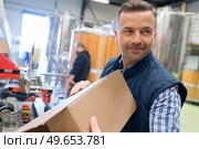 man holding cardboard box in factory dispatch department. Стоковое фото, агентство Ingram Publishing / Фотобанк Лори