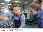 engineer helping female apprentice in factory. Стоковое фото, агентство Ingram Publishing / Фотобанк Лори