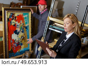 auctioneer and assistant rchecking auction goods. Стоковое фото, агентство Ingram Publishing / Фотобанк Лори