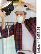 contractor wearing mask while using lamp to look into attic. Стоковое фото, агентство Ingram Publishing / Фотобанк Лори