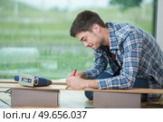 young male fitter measuring floorboard. Стоковое фото, агентство Ingram Publishing / Фотобанк Лори