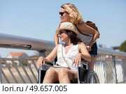 woman pushes friend in wheelchair on the beach. Стоковое фото, агентство Ingram Publishing / Фотобанк Лори