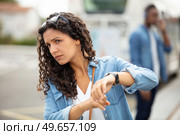 woman waiting for public transport checking the time on wristwatch. Стоковое фото, агентство Ingram Publishing / Фотобанк Лори