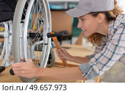 woman making an adjustment on a wheelchair. Стоковое фото, агентство Ingram Publishing / Фотобанк Лори