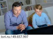 Adult and child engrossed watching television. Стоковое фото, агентство Ingram Publishing / Фотобанк Лори