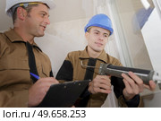 apprentice renewing of a silicone joint on a window. Стоковое фото, агентство Ingram Publishing / Фотобанк Лори
