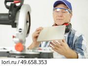 mature man assessing wood he has prepared with circular saw. Стоковое фото, агентство Ingram Publishing / Фотобанк Лори